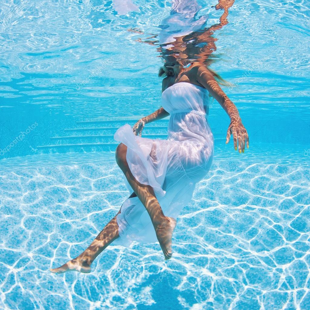 Underwater woman fashion portrait with white dress in swimming pool