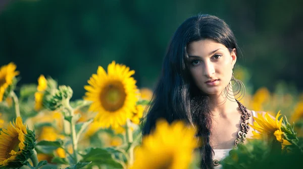 Junge schöne Frau in einem Sonnenblumenfeld mit weißem Kleid — Stockfoto