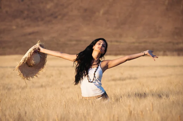 Joven mujer feliz en un campo de trigo con vestido blanco y sombrero de paja —  Fotos de Stock