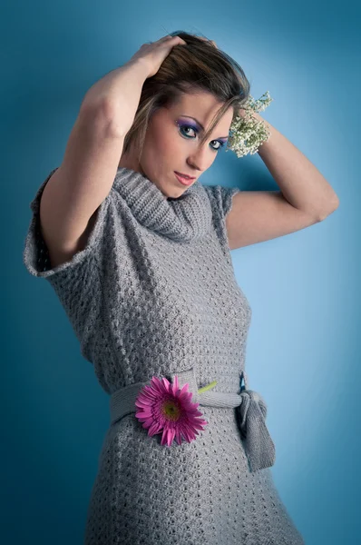 Retrato de menina bonita com flor de gerbera e vestido de lã contra fundo azul — Fotografia de Stock