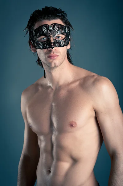 Portrait of young man shirtless with mask against dark background — Stock Photo, Image