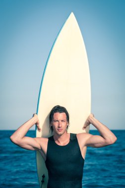 çekici genç adam portresi bir surfboard ile plajda sörf