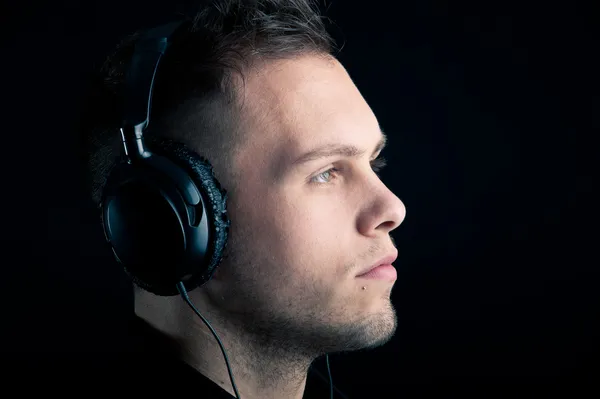 Profil rapproché de l'homme avec écouteurs sur fond noir — Photo