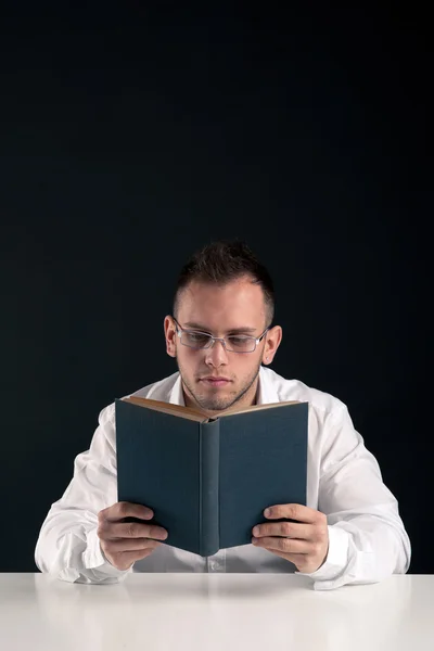 Young man reading a book against black background with copy space — Stock Photo, Image
