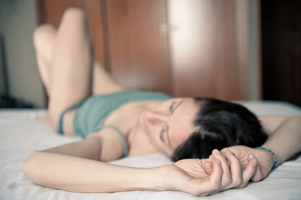 Portret zmysłowej kobiety leżąc na łóżku w pokoju hotelowym. Płytkiej głębi ostrości — Zdjęcie stockowe