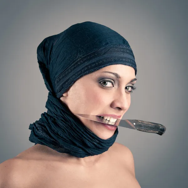 Veiled woman holding a knife against dark background — Stock Photo, Image