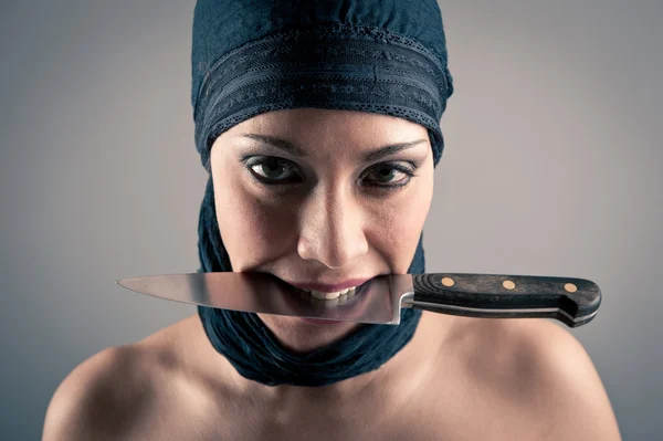 Beslöjad kvinna med en kniv mot mörk bakgrund — Stockfoto