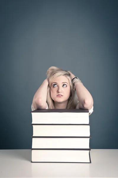 Young girl student with pile of books against dark background — Stock Photo, Image