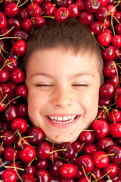 Kid glimlachend gezicht portret omringd door kersen — Stockfoto