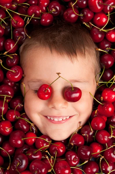 Kid glimlachend gezicht portret omringd door kersen — Stockfoto