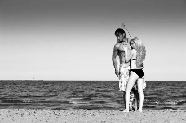 Coppia in spiaggia con tavola da surf. Immagine in bianco e nero — Foto Stock