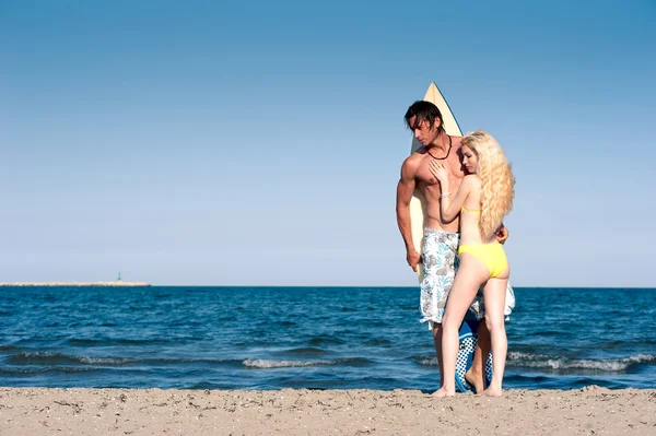 Pareja joven en la playa con tabla de surf con espacio para copiar —  Fotos de Stock