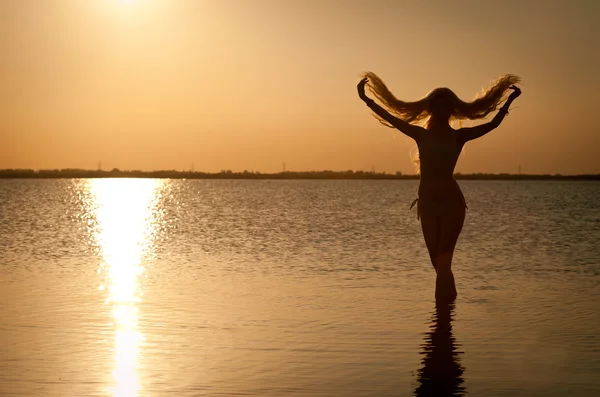 O tânără frumoasă care pozează pe plajă la apusul soarelui. Silouette — Fotografie, imagine de stoc