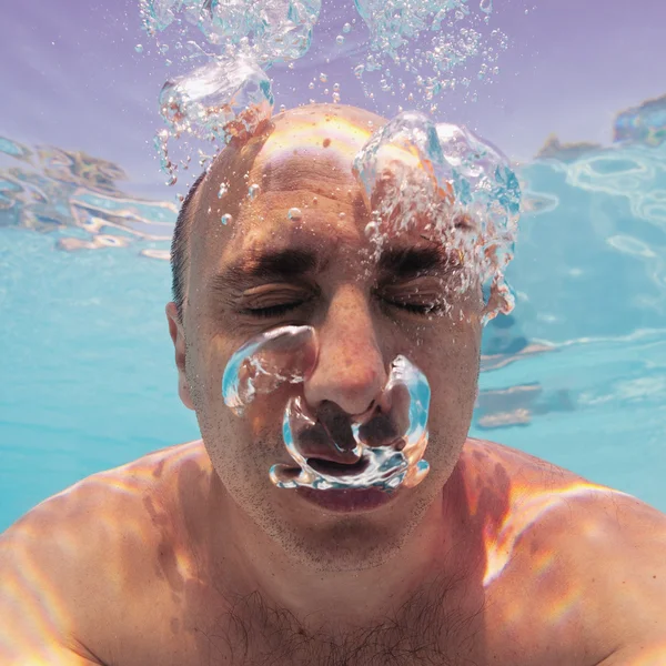 Underwater portrait of bald man with bubbles in a swimming pool — Stock Photo, Image