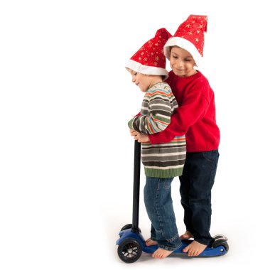 iki erkek birlikte Noel şapka ve scooter beyaz arka plan üzerinde oynama