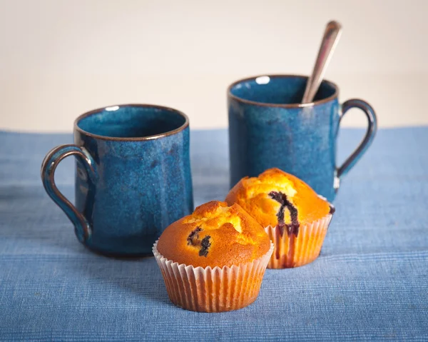 Blueberry muffins and cups on blue placemat — Stock Photo, Image