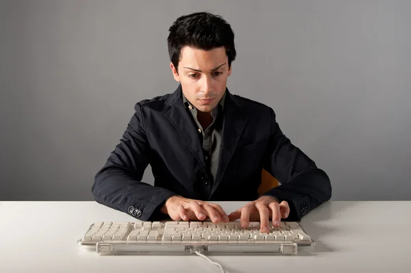 Портрет молодого чоловіка, який працює з комп'ютером на сірому фоні — стокове фото