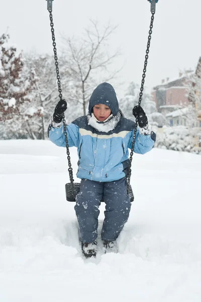 Kid swinging in the snow — Stock Photo, Image