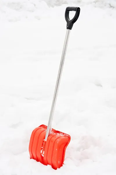 Оранжевая снежная лопата застряла в сугробе — стоковое фото