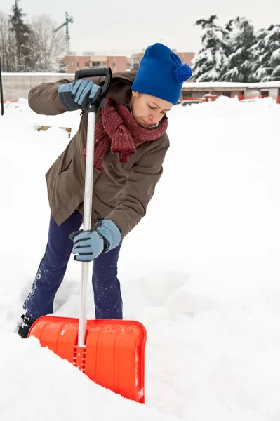 Женщина убирает снег с тротуара — стоковое фото