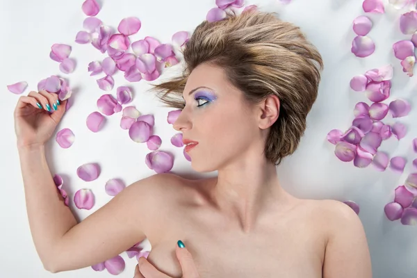 Portrett av vakker, naken jente med rosenblader mot hvit bakgrunn – stockfoto