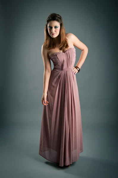 Portrait of beautiful girl with pink dress against dark background — Stock Photo, Image