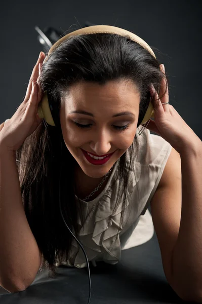 Menina bonita ouvindo música contra fundo escuro — Fotografia de Stock