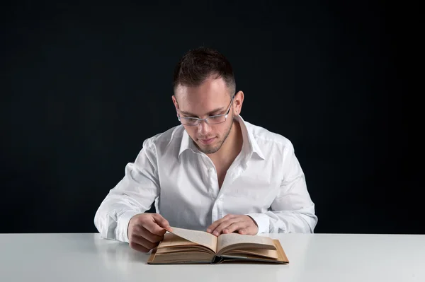 Young man reading a book against black background — Stock Photo, Image