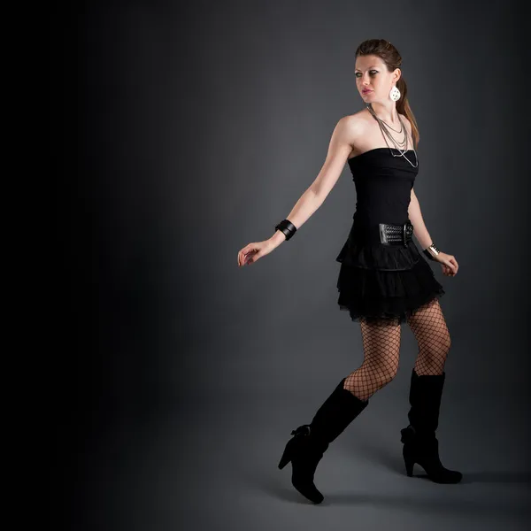 Mooi meisje met zwarte jurk tegen donkere achtergrond ontsnappen — Stockfoto
