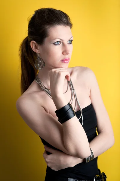 Intense portrait of beautiful girl with black dress against yellow background — Stock Photo, Image