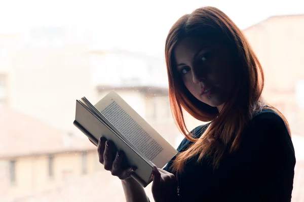 读一本书在窗口的红色女孩的浪漫肖像 — 图库照片