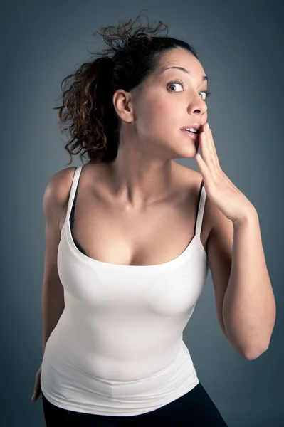 Portrait of surprised brunette curly girl with white vest on dark background — Stock Photo, Image