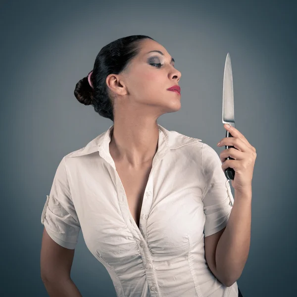Sexy morena mujer sosteniendo un cuchillo contra fondo oscuro —  Fotos de Stock