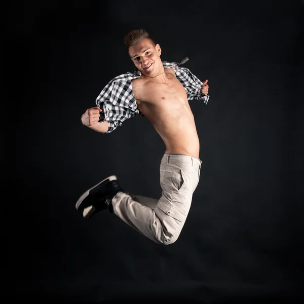 Umping young man portrait with plaid shirt against black background — Stock Photo, Image