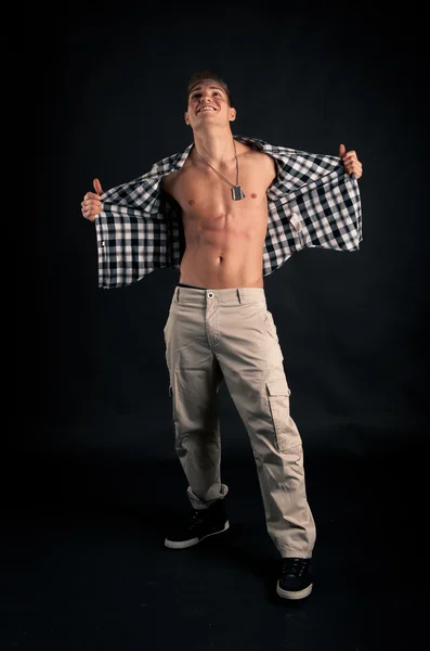 Studio portrait of confident young man with plaid shirt against black background — Stock Photo, Image