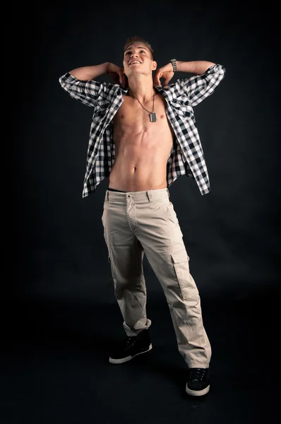 Studio portrait of confident young man with plaid shirt against black background — Stock Photo, Image