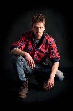 genç adam portresi siyah arka plan üzerinde çömeldi.