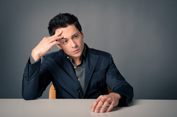 Worried man with desk against dark background