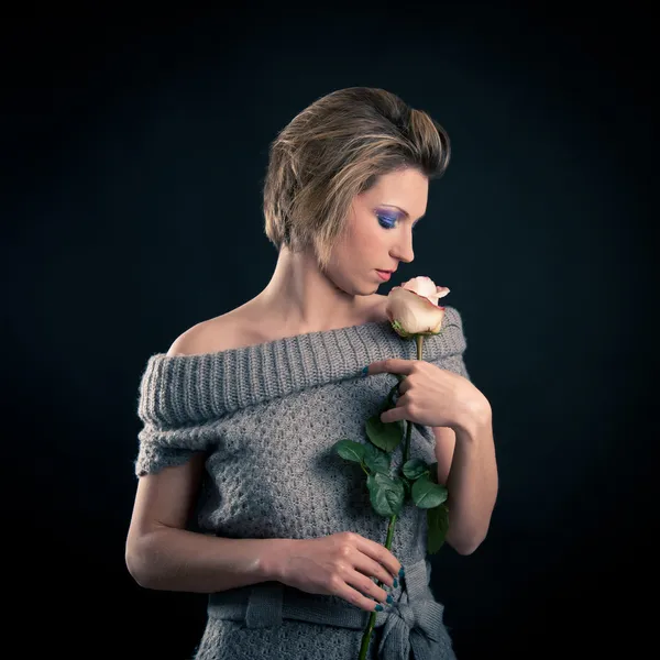 Retrato de menina bonita com flor de rosa e vestido de lã contra fundo preto — Fotografia de Stock