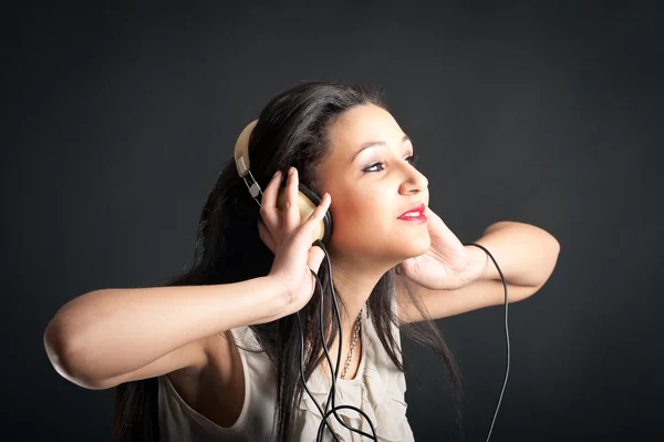 Beautiful girl listening to music against dark background — Stock Photo, Image