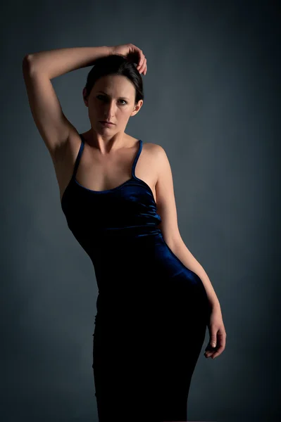 Elegante vrouw in zwarte jurk tegen donkere achtergrond — Stockfoto