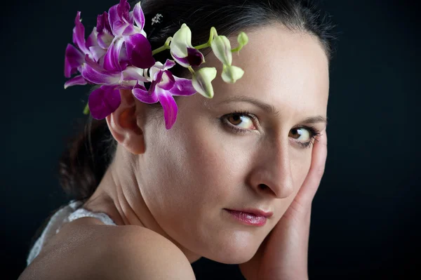 Close up portrait of beautiful girl with orchid pink flower — Stock Photo, Image