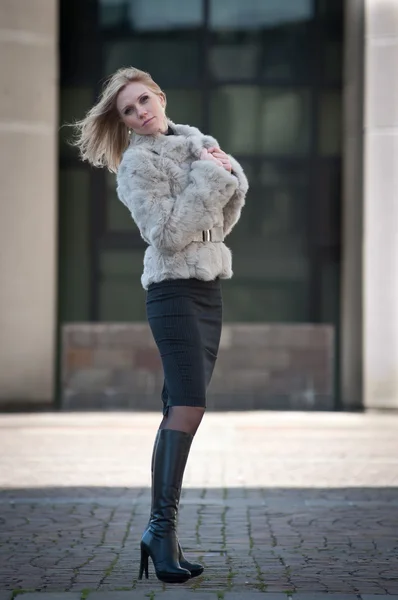 Young attractive businesswoman with fur in front of modern business building — Stock Photo, Image