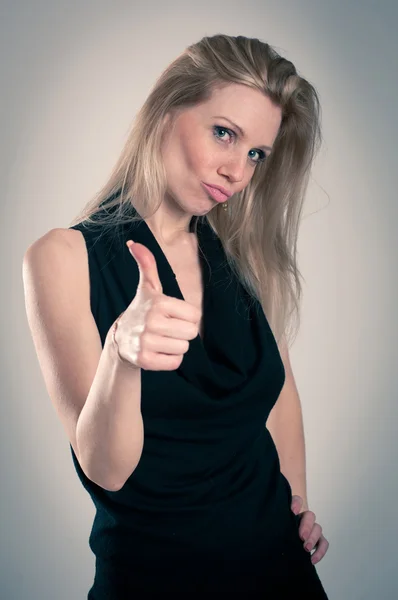 Счастливая блондинка белая женщина с элегантным черным платьем и большим пальцем вверх — стоковое фото