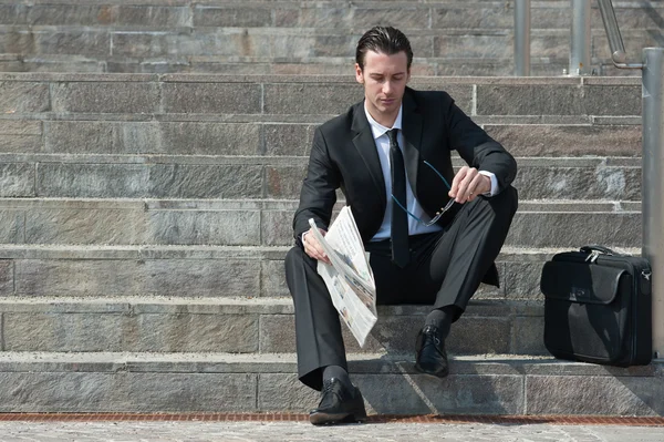 Jonge zakenman met krant zittend op de trap — Stockfoto