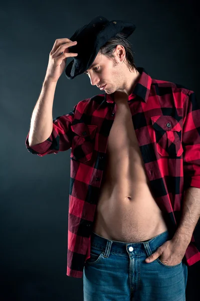 Studio portrait of confident young man with plaid shirt against dark background — Stock Photo, Image