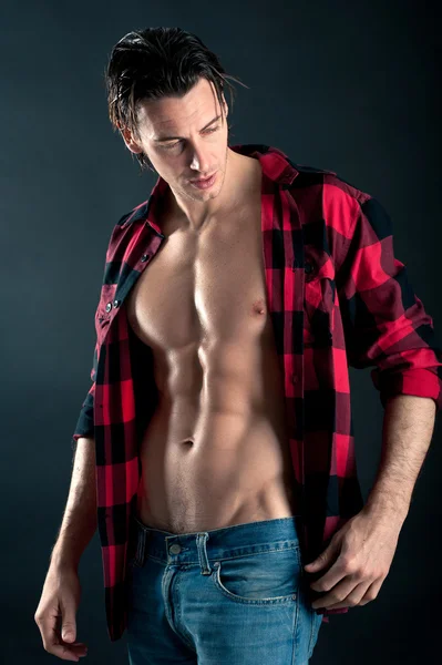 Confident young man with plaid shirt against dark background — Stock Photo, Image