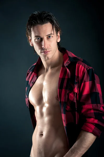 Confident young man with plaid shirt against dark background — Stock Photo, Image