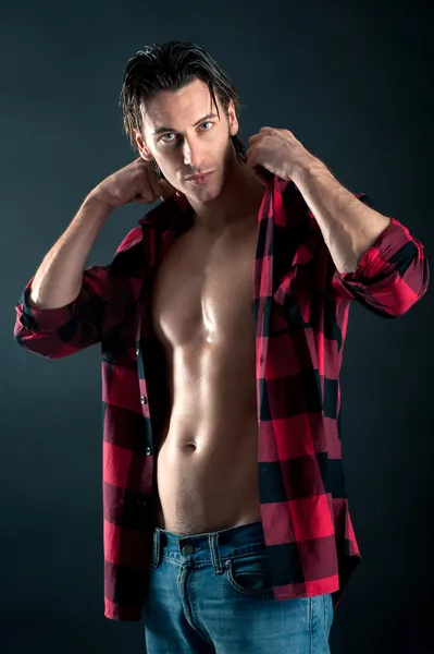 Confident young man with plaid shirt against dark background — Stock Photo, Image