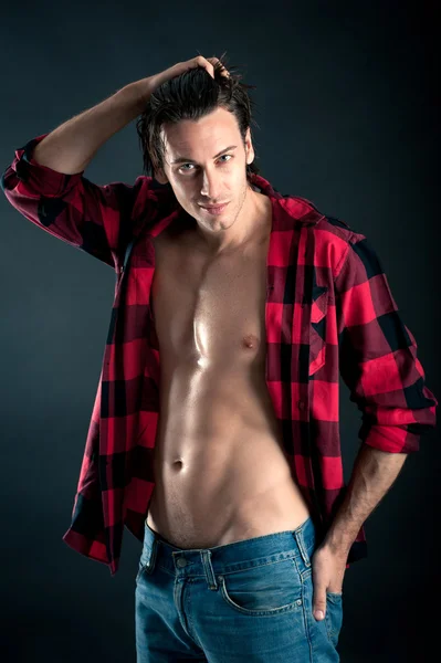 Confident young man with plaid shirt against dark background — Stock Photo, Image